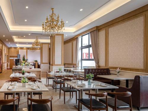 un ristorante con tavoli, sedie e lampadario a braccio di Vienna Hotel(Shenzhen Shajing Jingjinbaina Branch) a Shenzhen