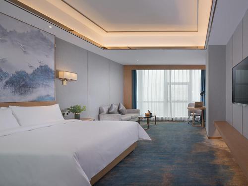 - une chambre avec un grand lit blanc et un canapé dans l'établissement Venus Royal Hotel(Foshan Kuiqi Road Metro Station), à Foshan