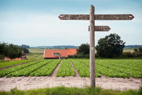 a wooden sign in front of a field of crops at Grenshotel de Jonckheer in Ossendrecht