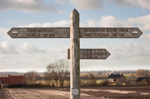 a wooden street sign in the middle of a field at Grenshotel de Jonckheer in Ossendrecht