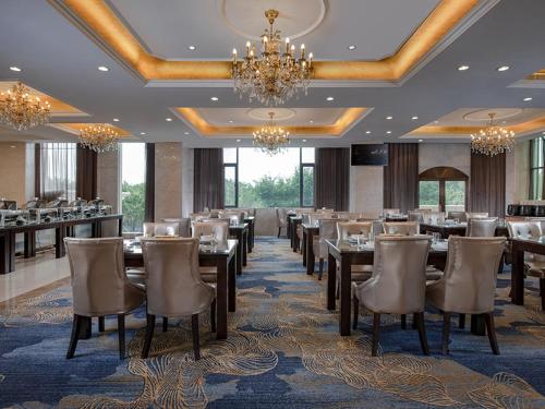una sala da pranzo con tavoli, sedie e lampadario a braccio di Vienna Hotel (Quanzhou West Lake Store) a Quanzhou
