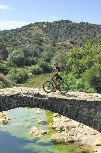 a man riding a bike on a bridge over a river at Galini Breeze in Agia Galini