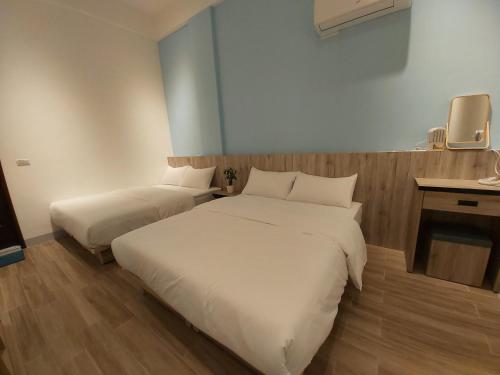 a hotel room with two beds and a tv at Haichin&Haiting B&B in Donggang