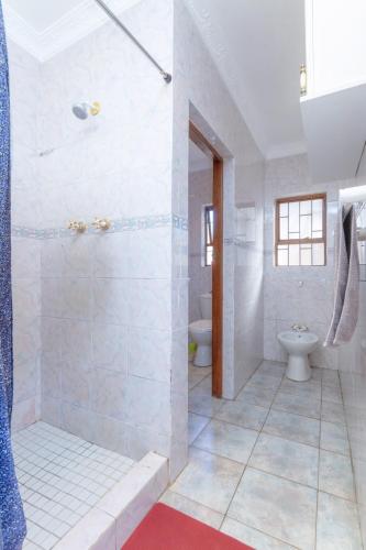 a white bathroom with a shower and a toilet at Linden Guest House in Johannesburg