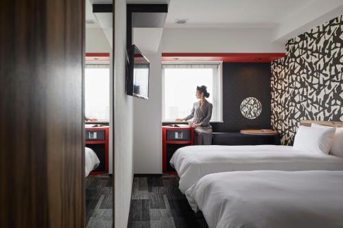 a woman standing in a hotel room with two beds at the b asakusa in Tokyo