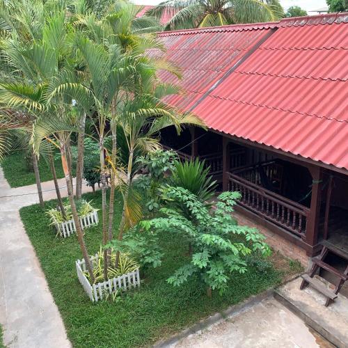 a building with palm trees and a red roof at Dalom Guesthouse in Don Det