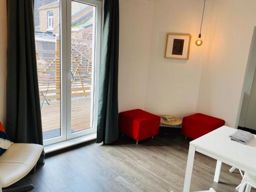 a room with a window and a table and red chairs at L’atelier St Remacle in Liège
