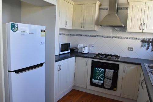 達博的住宿－Fitzroy haven，厨房配有白色橱柜和白色冰箱。