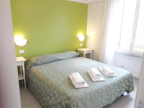 ローマにあるResidence Europa - Licia Apartmentの緑のベッドルーム(タオル付きのベッド付)