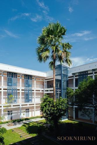 a palm tree in front of a building at SOOKNIRUND HOTEL in Chiang Rai