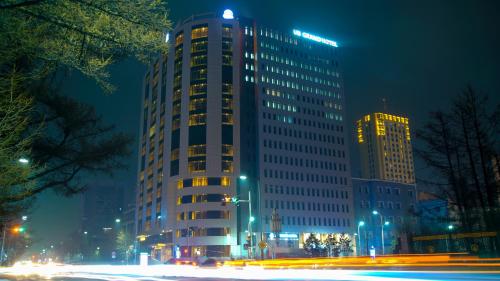 ウランバートルにあるUB Grand Hotelの高い建物は夜にライトアップされる