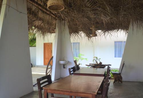 a dining room with a table and a straw roof at D'Villa Garden House in Jaffna