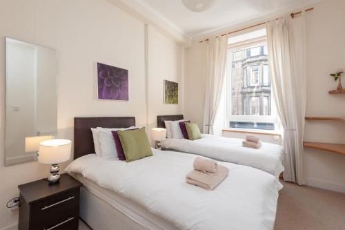2 camas en una habitación blanca con ventana en Edinburgh Rossie Place Apartment, en Edimburgo