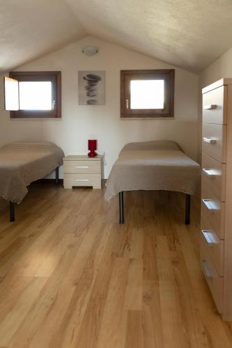 two beds in a room with wooden floors at Case Fiorite in Riola Sardo