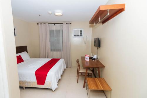 a bedroom with a bed and a table and a desk at RedDoorz near Osmena Highway 1 in Manila