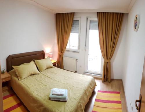 a bedroom with a bed and two windows at Gorgeous Apartment with City View in the City Center in Pristina