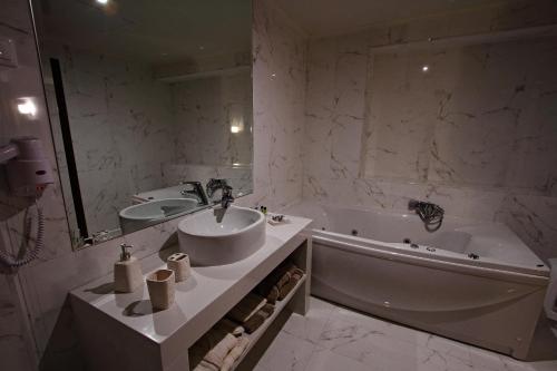 a white bathroom with a sink and a tub and a sink at Siris Hotel in Serres