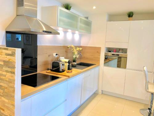 a kitchen with white cabinets and a sink at Appartement Cosy Calme Central-Terrasse Proche Palais in Cannes
