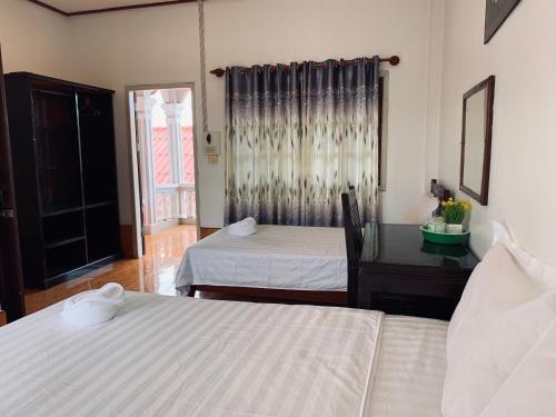 a room with two beds and a desk and a window at Dalom Guesthouse in Don Det
