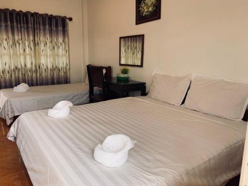 two beds with hats on top of them in a room at Dalom Guesthouse in Don Det