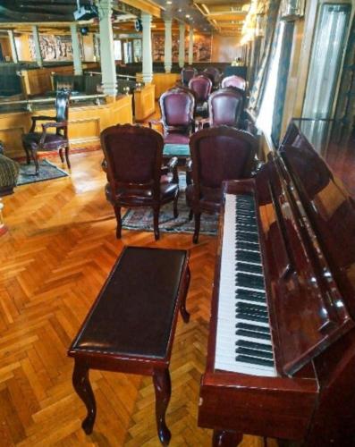 a piano and chairs in a room with a bar at King Tut I Nile Cruise - Every Monday 4 Nights from Luxor - Every Friday 7 Nights from Aswan in Luxor