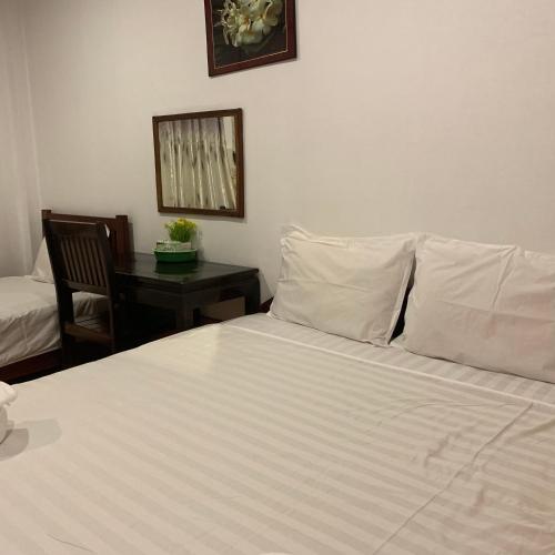 a bedroom with a bed with white sheets and a desk at Dalom Guesthouse in Don Det