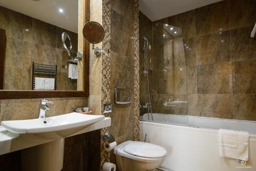 a bathroom with a sink and a toilet and a tub at Apartament Alpin resort etaj 7 in Poiana Brasov