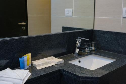 a bathroom counter with a sink and a mirror at Savoy Hotel Mactan in Mactan