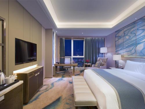 a hotel room with a large bed and a television at Wanda Vista Nanning in Nanning