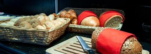 Una mesa con cestas de pan y una espátula en Bastion Hotel Rotterdam Alexander, en Róterdam