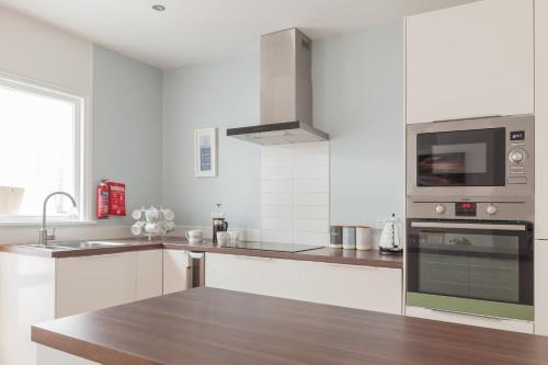 een witte keuken met een wastafel en een magnetron bij Sea Glimpses with garden, beachhut, parking in Broadstairs