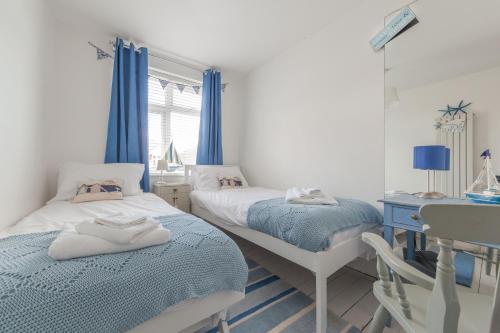a bedroom with two beds and a desk and a table at Sea Glimpses with garden, beachhut, parking in Broadstairs
