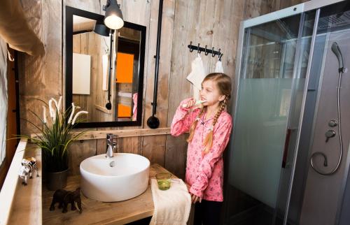 une femme debout dans une salle de bain se brossant les dents dans l'établissement Serengeti Park Resort, à Hodenhagen