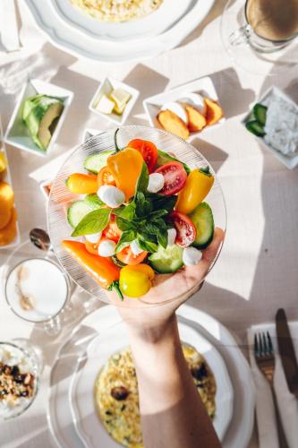 a person holding a bowl of fruit on a table at Cnaan Village Boutique Hotel & Spa in Had Nes
