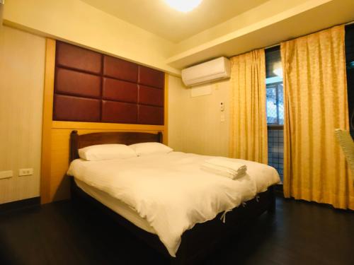 a bedroom with a bed with white sheets and a window at Love Feng Jia Apartment Hotel in Taichung