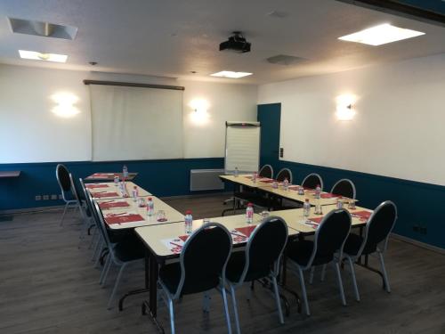 a conference room with tables and chairs and a whiteboard at Kyriad Rouen Sud - Oissel in Saint-Étienne-du-Rouvray