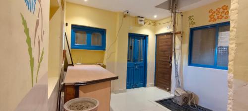 une cuisine avec une porte bleue et des murs jaunes dans l'établissement Shivam Guest House, à Jodhpur