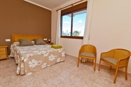 um quarto com uma cama, 2 cadeiras e uma janela em Bahia Azul VyB em Denia