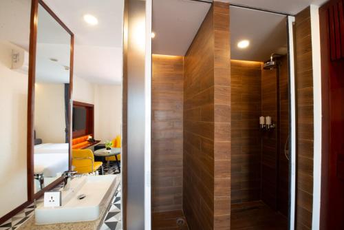 a bathroom with a shower with a sink and a mirror at The Twizt - Lifestyle Hostel & Hotel in Siem Reap