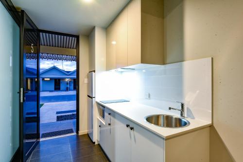 cocina blanca con fregadero y ventana en Aloha Central Premium Studios en Mount Gambier