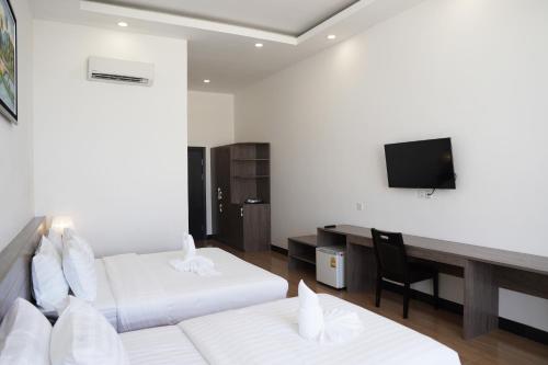 a hotel room with two beds and a desk at Apple Hotel Three - Phnom Penh in Phnom Penh