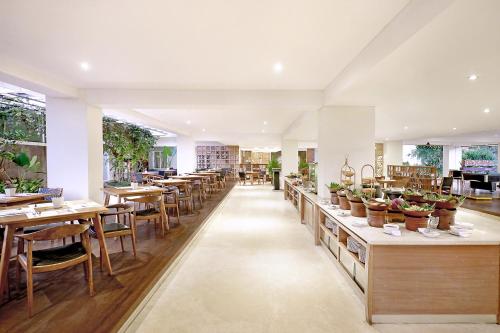 a restaurant with tables and chairs and potted plants at FOX Hotel Jimbaran Beach Bali in Jimbaran