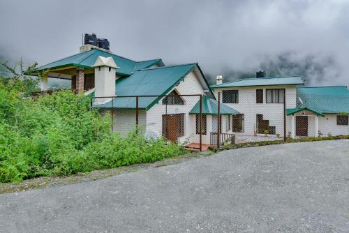 a group of houses with green roofs next to a road at Karinya Villas in Nainital