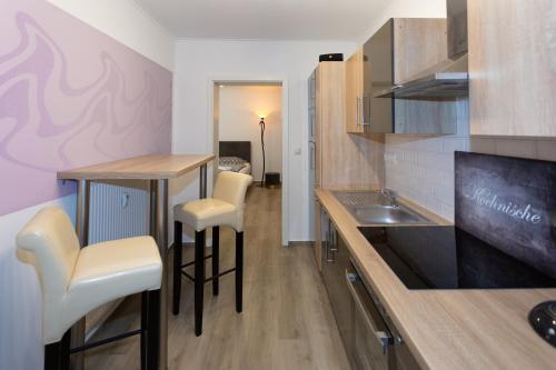 a kitchen with two bar stools and a sink at Ferienwohnungen am Markt - Der Sachsenhof in Bad Liebenwerda