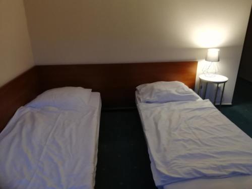 two beds with white sheets in a room at Hostel Ratuszowy in Bydgoszcz