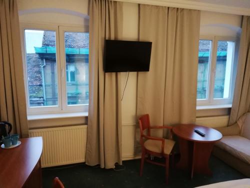 a hotel room with a table and a couch and a television at Hostel Ratuszowy in Bydgoszcz