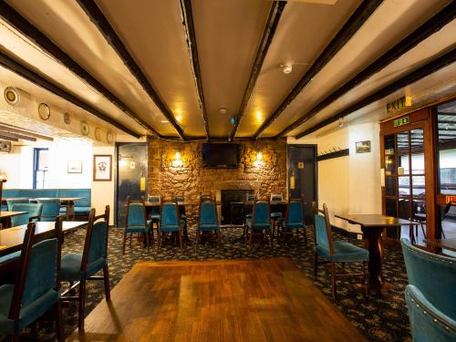 a dining room with tables and chairs and a fireplace at Longforgan Coaching Inn in Dundee