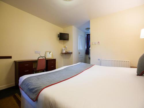 a bedroom with a large white bed and a desk at Longforgan Coaching Inn in Dundee