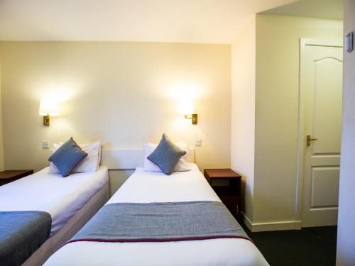 two beds in a hotel room with blue pillows at Longforgan Coaching Inn in Dundee