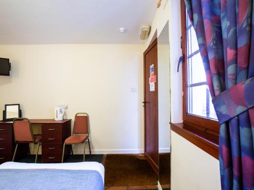 a room with a bed and a desk and a window at Longforgan Coaching Inn in Dundee